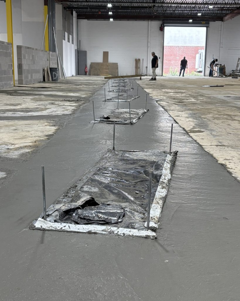 Fresh concrete poured around in ground lift in an existing shop