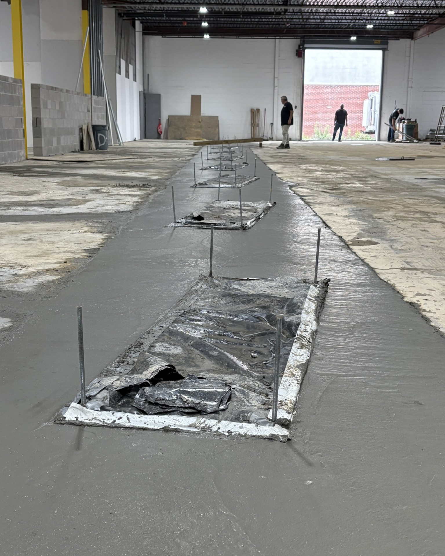 Fresh concrete poured around in ground lift in an existing shop